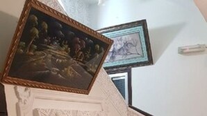 En trappe med en dekorativ vægpanel, et indrammet maleri og en stol.