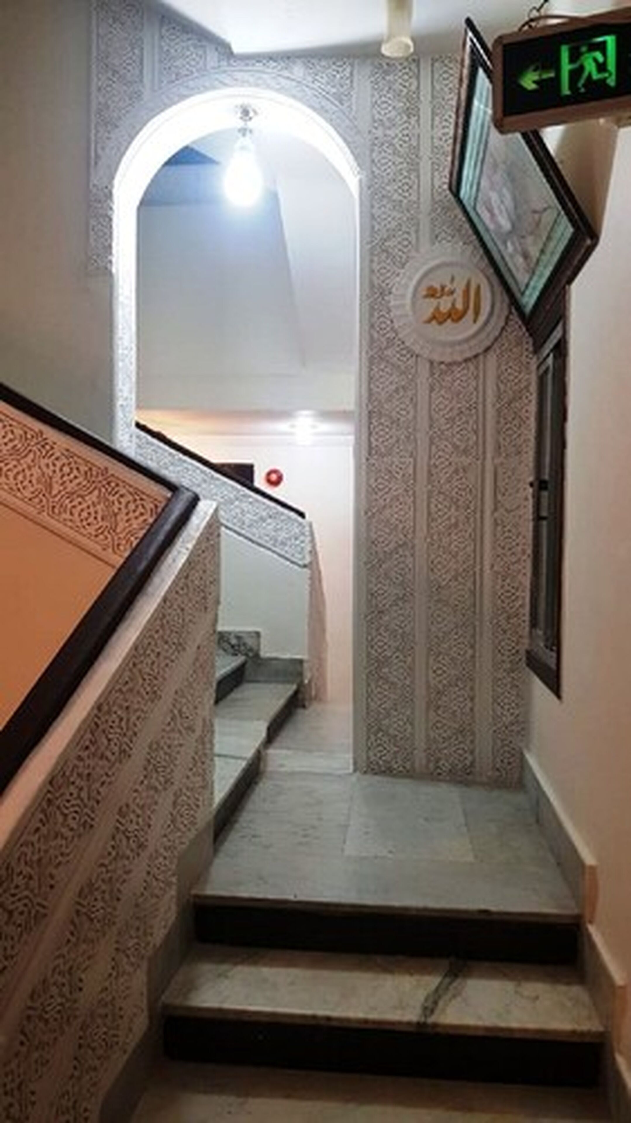 A staircase with ornate wall designs and a sign with Arabic script.