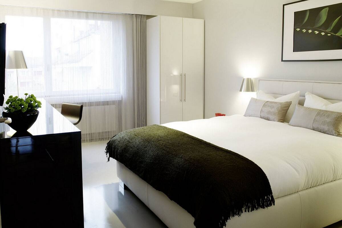 Una habitación de hotel moderna con una cama grande, un escritorio y una ventana con cortinas.