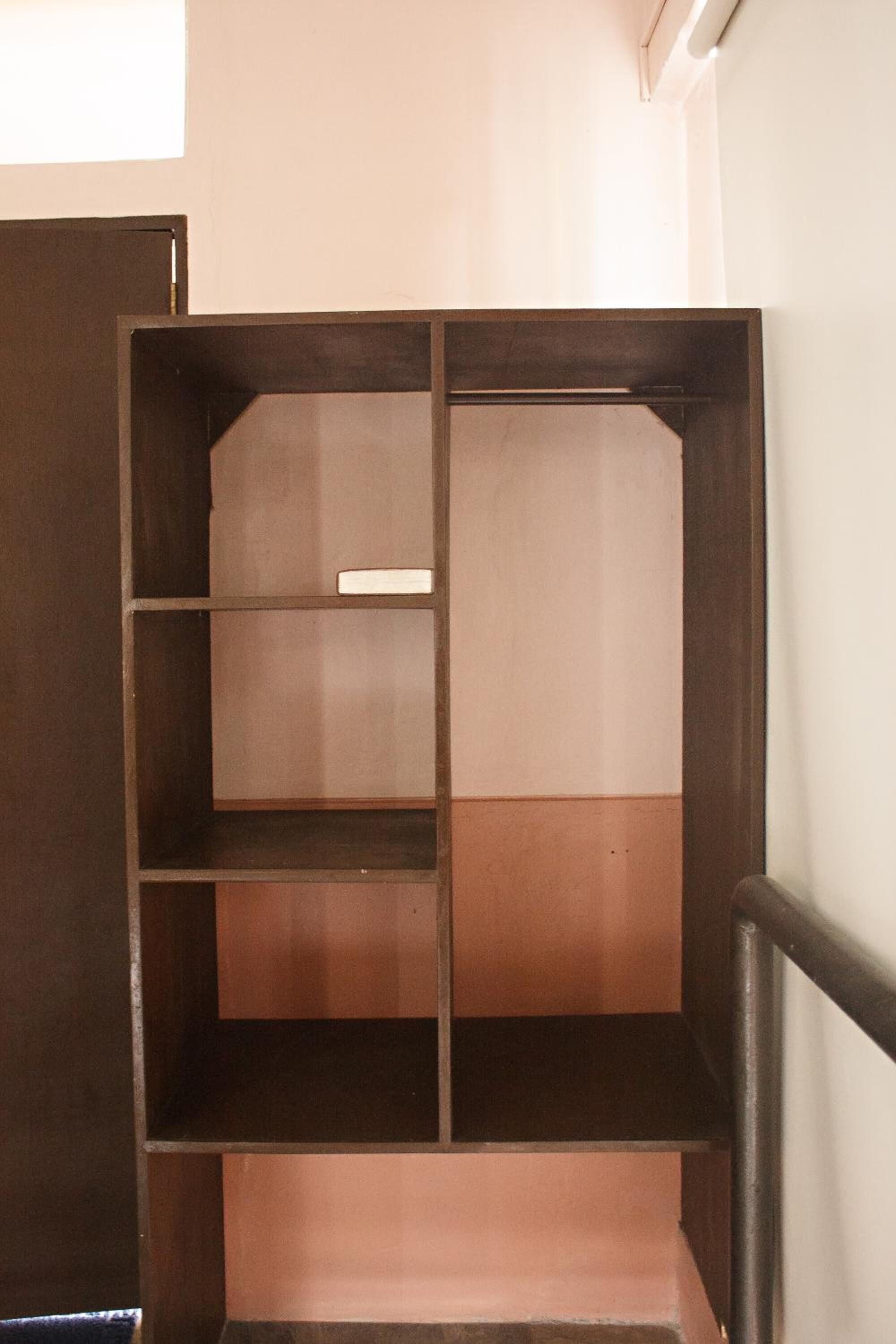 Een hoek van een kamer met een houten kast en een witte muur.