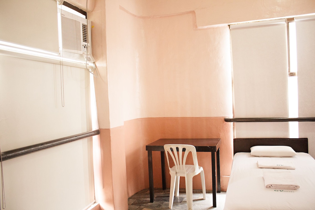 A hotel room with a bed, a desk, and a chair.