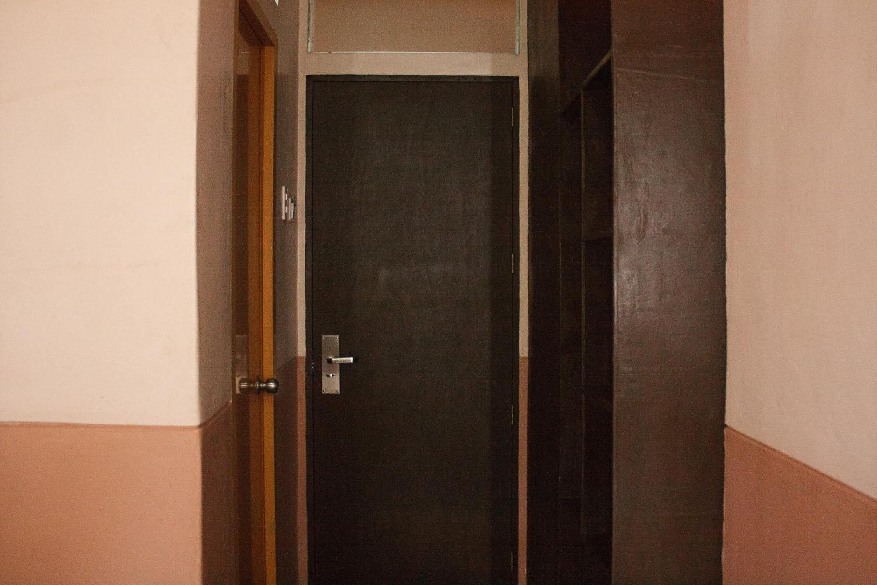 A closed door with a metallic handle and a keyhole, set in a corner with a beige and brown wall.