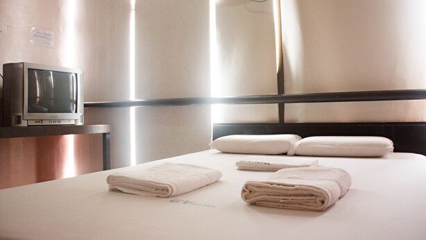 A hotel room with a bed, towels, a television, and a window with curtains. - GV Hotel Ormoc (Ormoc)