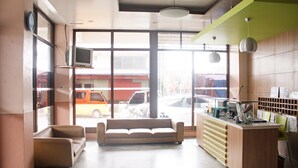 A lobby with a sofa, a reception desk, and large windows overlooking a street. - GV Hotel Ormoc (Ormoc)