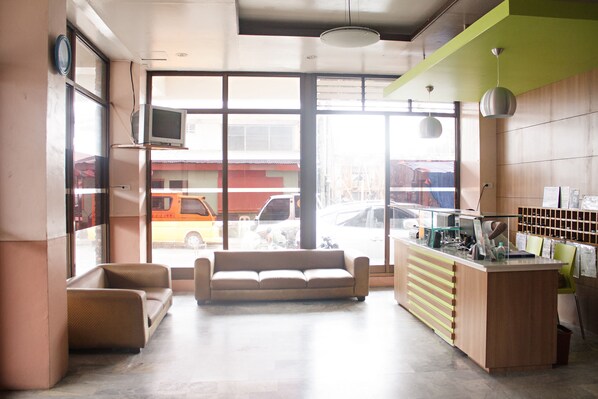 A lobby with a sofa, a reception desk, and large windows overlooking a street. - GV Hotel Ormoc (Ormoc)