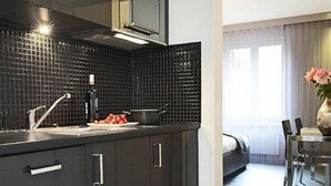 A modern kitchen with dark cabinetry, a stainless steel range hood, and a black tiled backsplash. - VISIONAPARTMENTS Zurich Cramerstrasse 2-6 (Zürich)