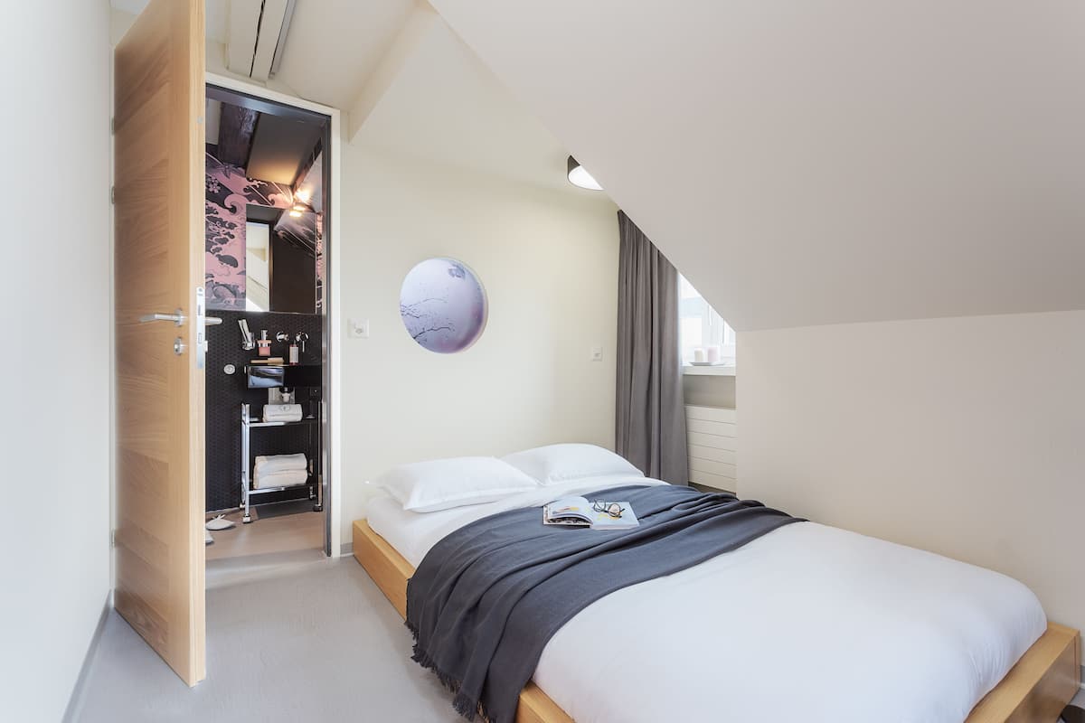 A bedroom with a bed, a wardrobe, a mirror, and a globe on the wall.