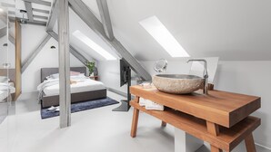 A modern bedroom with a skylight, a large wooden vanity with a stone basin, and a bed with a grey headboard. - VISIONAPARTMENTS Zurich Cramerstrasse 2-6 (Zürich)