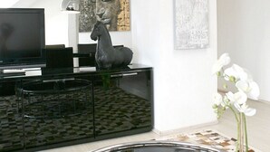 A modern living room with a flat-screen TV, a decorative horse sculpture, and a large abstract painting on the wall. - VISIONAPARTMENTS Zurich Cramerstrasse 2-6 (Zürich)