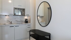 A modern kitchen with a built-in microwave, a coffee maker, and a round mirror on the wall. - VISIONAPARTMENTS Zurich Freyastraße (Zürich)