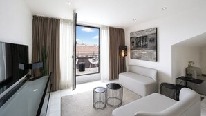 A modern hotel room with a large window, a flat-screen TV, a sofa, a small table, and a painting on the wall. - VISIONAPARTMENTS Zurich Freyastraße (Zürich)