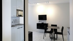 A modern kitchen with a built-in microwave and a dining area with a table and chairs. - VISIONAPARTMENTS Zurich Freyastraße (Zürich)