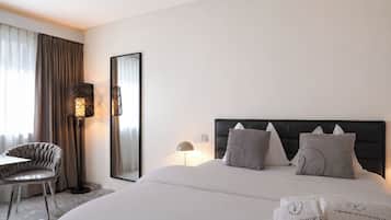 A hotel room with a bed, a chair, a desk, and a large mirror.