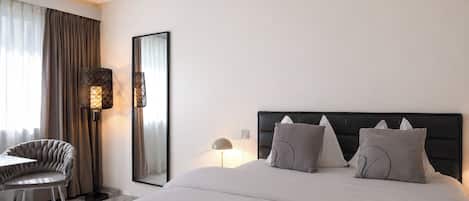 Une chambre d’hôtel avec un lit, une chaise, un bureau et un grand miroir.