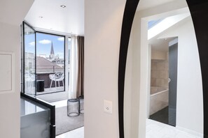 Un intérieur moderne avec un balcon, une vue sur la ville et un aperçu d’une salle de bain.