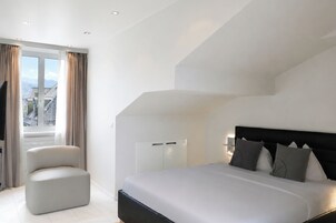 Un dormitorio moderno con una cama grande, una zona de estar y vistas a la ciudad desde la ventana.
