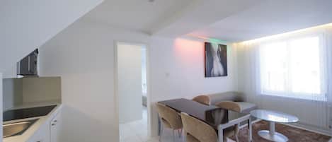 Une cuisine moderne dotée d’un four encastré et d’un coin repas avec une table et des chaises.