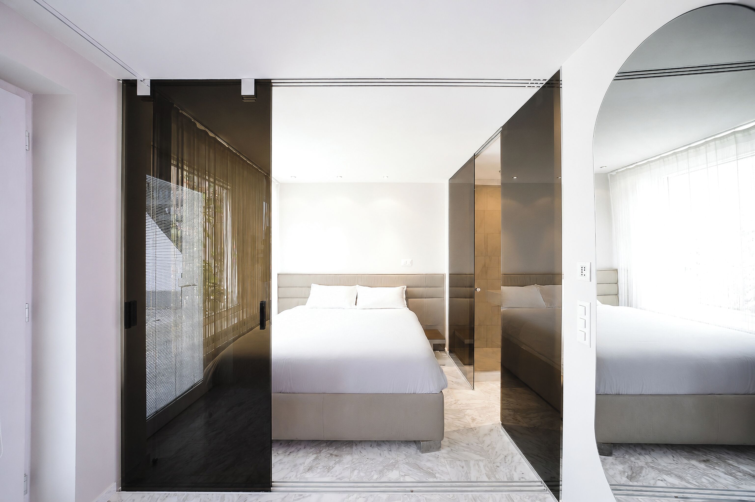 Un dormitorio moderno con una cama grande, un vestidor y un box de ducha de vidrio.