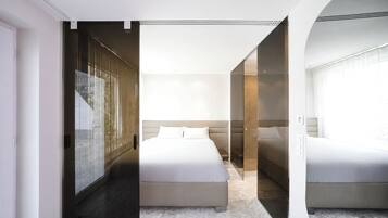 Un dormitorio moderno con una cama grande, un vestidor y un box de ducha de vidrio.