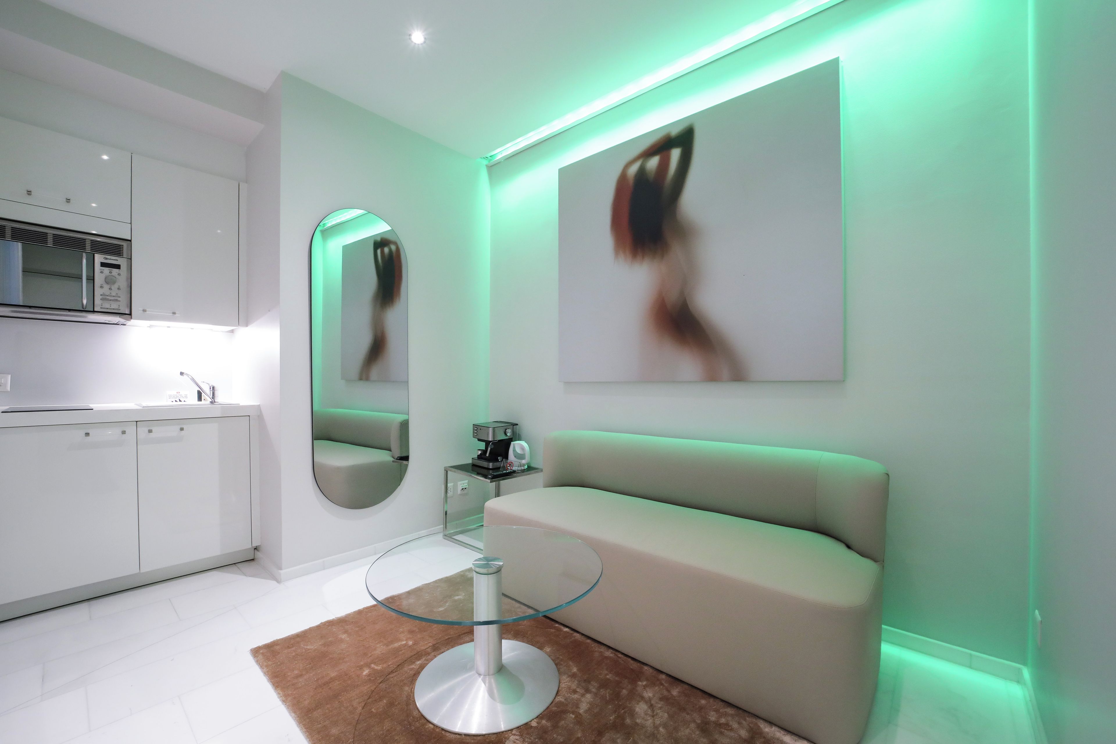 A modern kitchen with built-in appliances, a glass-top coffee table, and a sofa.