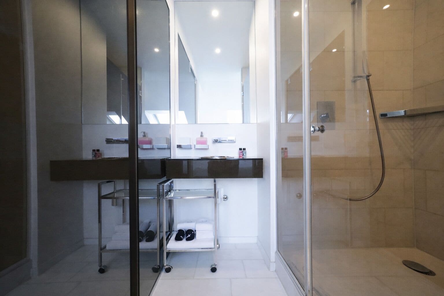A modern bathroom with a glass shower enclosure, a vanity with a mirror, and a shoe rack.