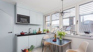 A modern kitchen with a built-in oven, a dining table with chairs, and a view of the city through large windows. - VISIONAPARTMENTS Zurich Zweierstrasse (Zürich)