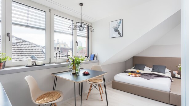 A modern bedroom with a bed, bedside table, and a window with blinds. - VISIONAPARTMENTS Zurich Zweierstrasse (Zürich)