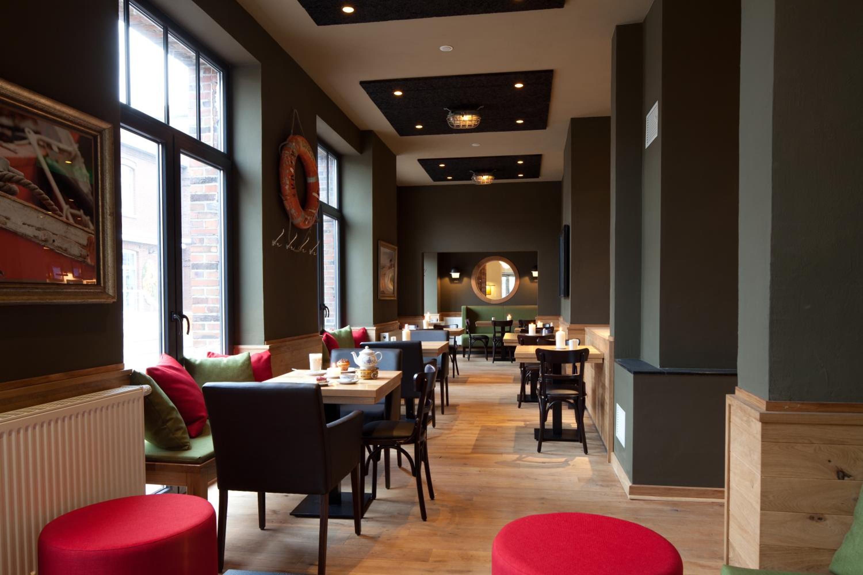 Ein Restaurantinneres mit hohen Decken, Holzböden und einer Mischung aus Sitzgelegenheiten, darunter Tische und Essecken.