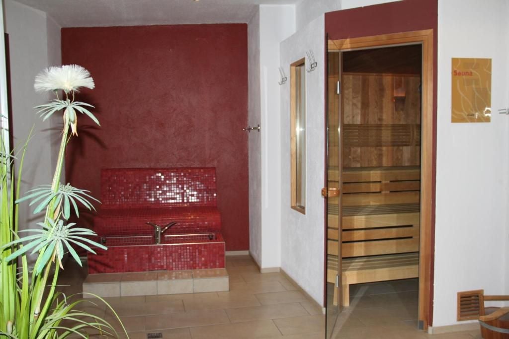 A spa area with a red tiled bench, a wooden sauna door, and a sign labeled 'Sauna'.
