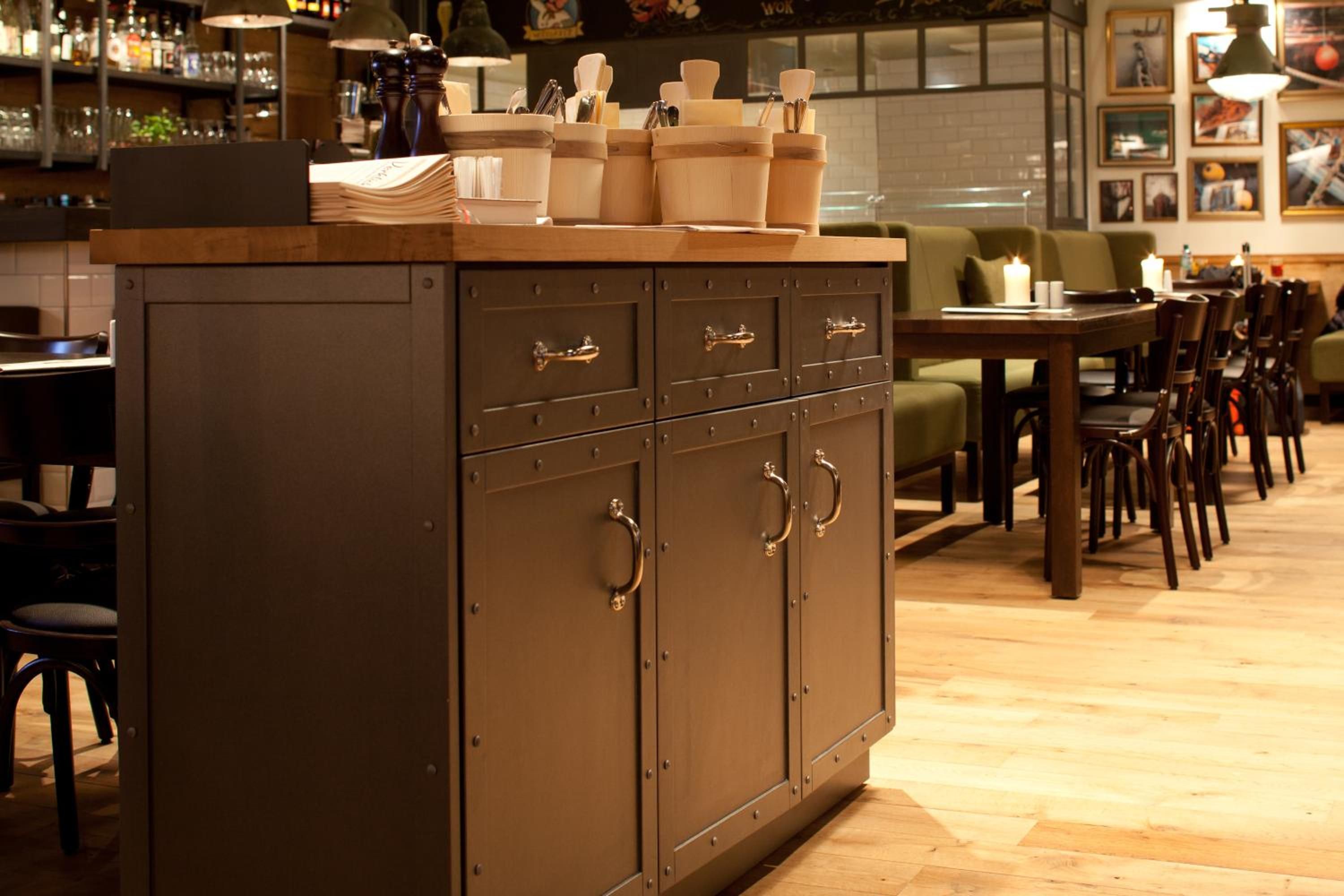 Una zona de bar con un mueble de madera, estanterías con botellas y un comedor con sillas y mesas.