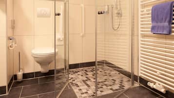 A modern bathroom with a glass shower enclosure, a toilet, and a towel rack with a towel.