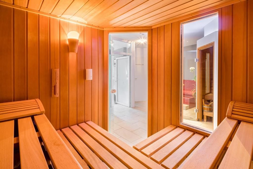 Una sauna amb seients de fusta i una porta de vidre que dona a un passadís.