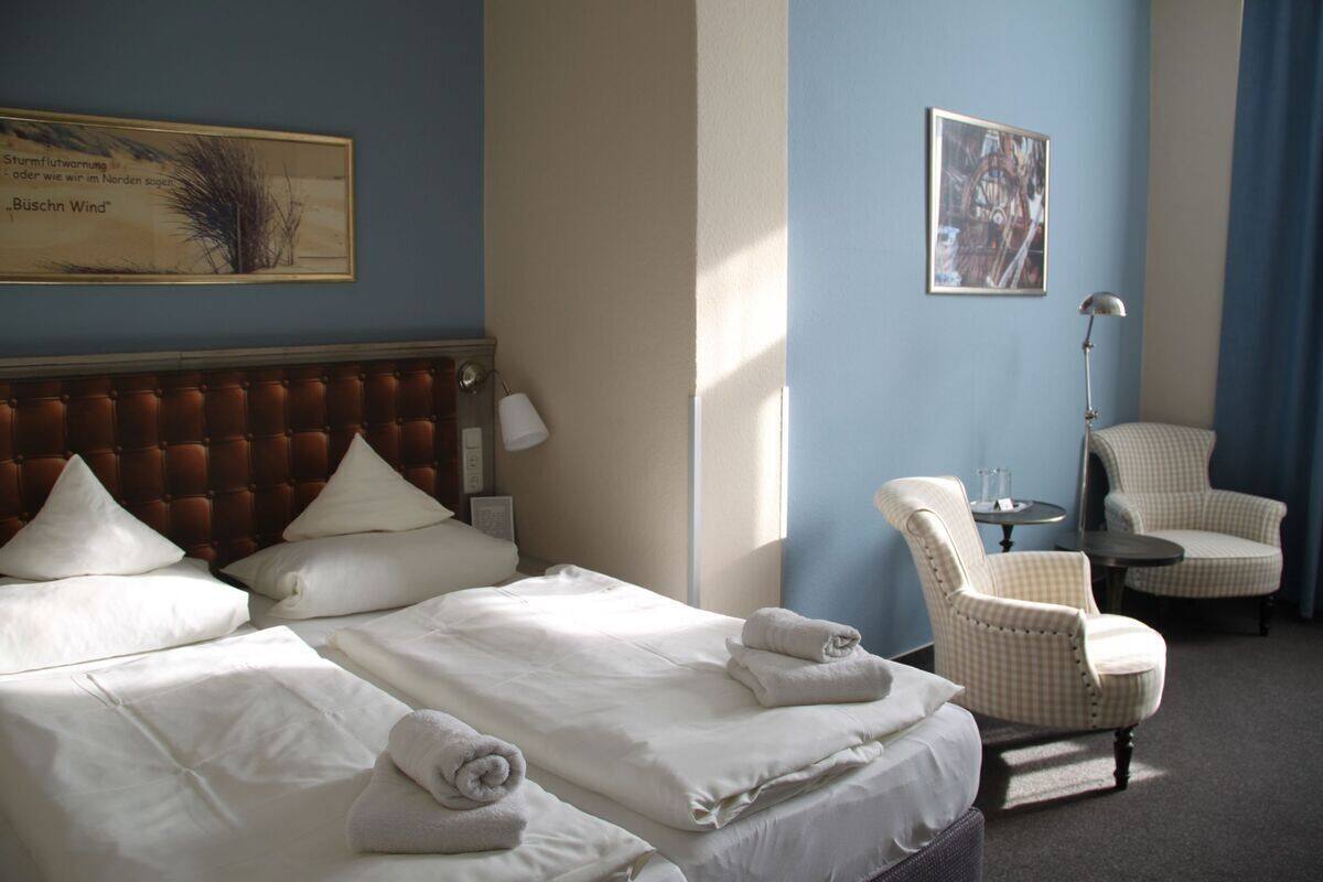 A hotel room with a large bed, two bedside tables, a chair, and a painting on the wall.