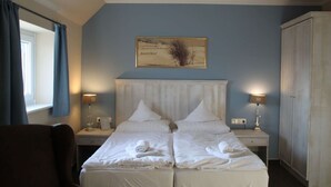 Ein Hotelzimmer mit zwei Betten, einem großen Kleiderschrank und einem Bild an der Wand.