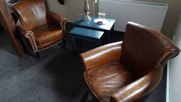 Una habitación con dos sillones de cuero, una mesita con lámpara y un radiador.
