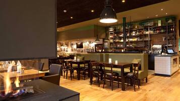 A restaurant with a bar area, wooden furniture, and a fireplace.