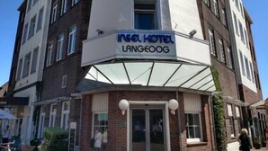 Ein Hotel namens „Insel Hotel Langeoog“ mit modernem Design, das einen markanten Eingangsbereich und zahlreiche Fenster zeigt.
