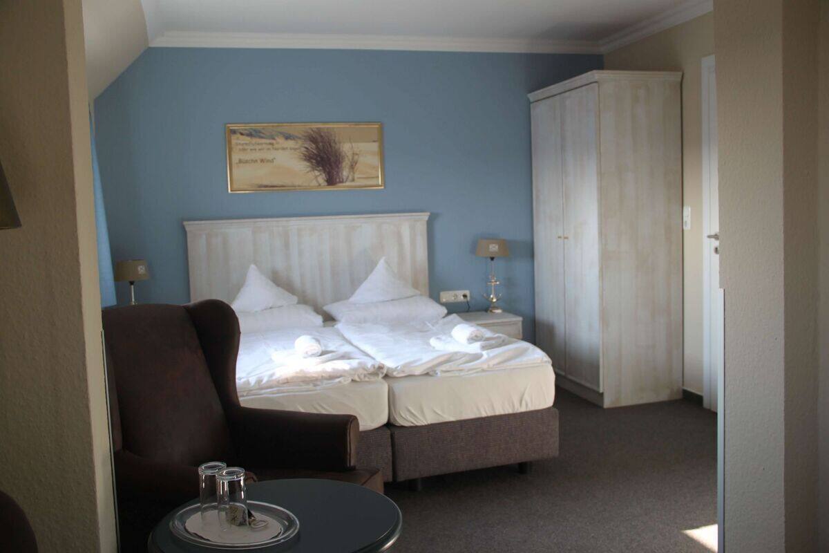 A hotel room with a bed, a chair, a small table with a tray, and a wardrobe.