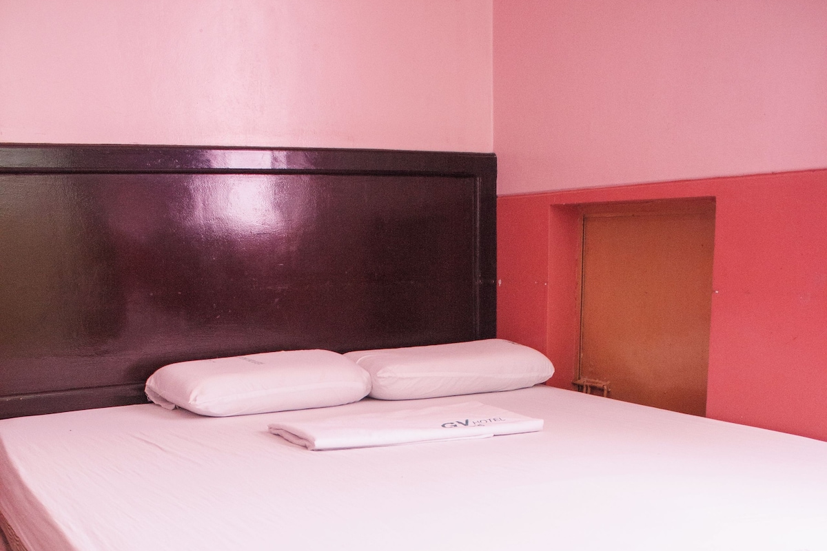 A bed with a mattress and pillows, a headboard, and a wooden floor.