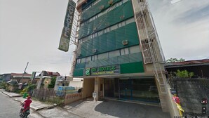 Een hotel met meerdere verdiepingen, met een groene gevel en een bordje met de tekst 'GV Hotels'.