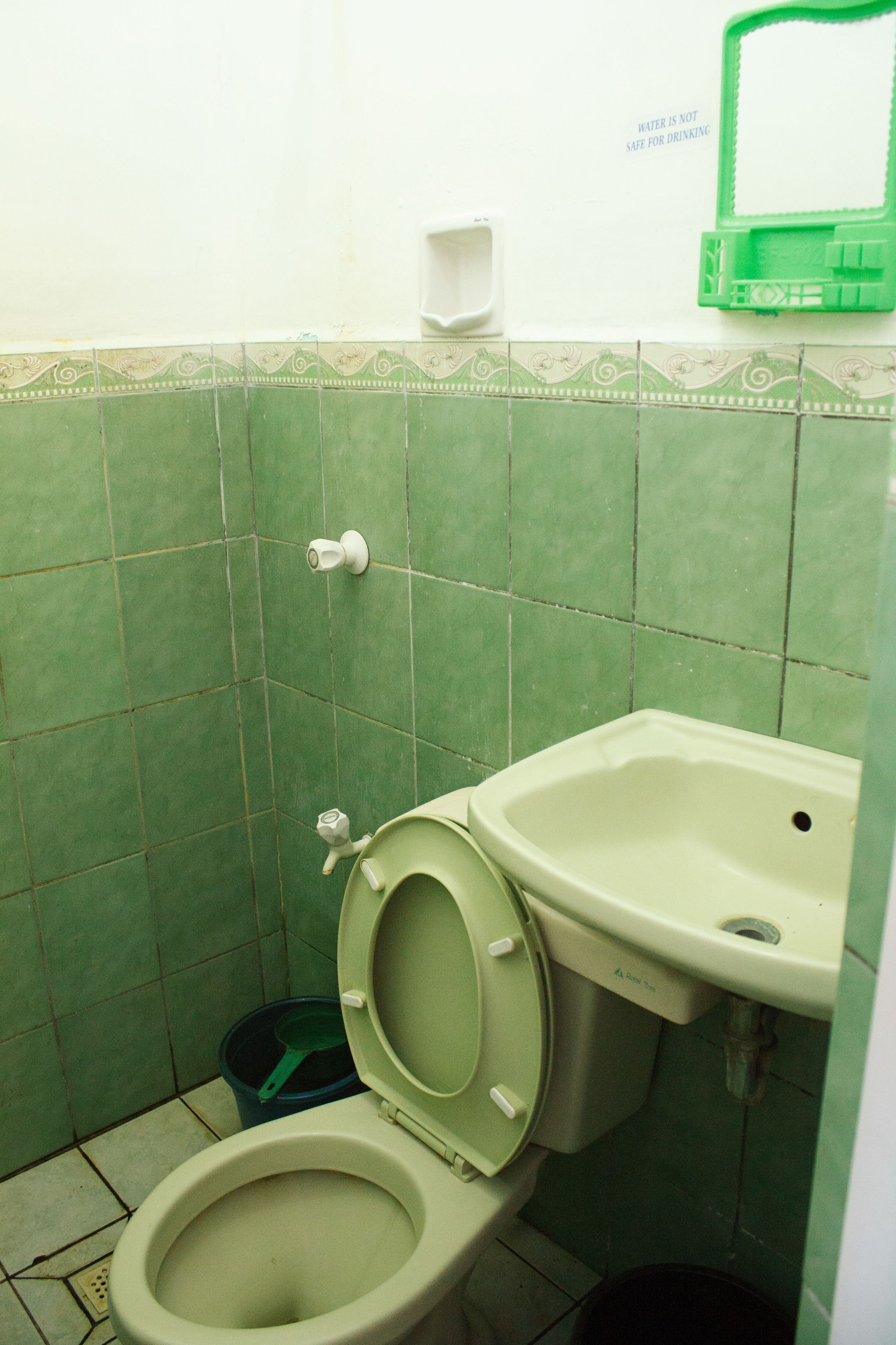 Ein Badezimmer mit Toilette, Waschbecken und grünen Fliesen.