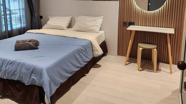 A modern bedroom with a large bed, a bedside table, a mirror, and a view of the outdoors. - B & B Patong Beach House (Patong)