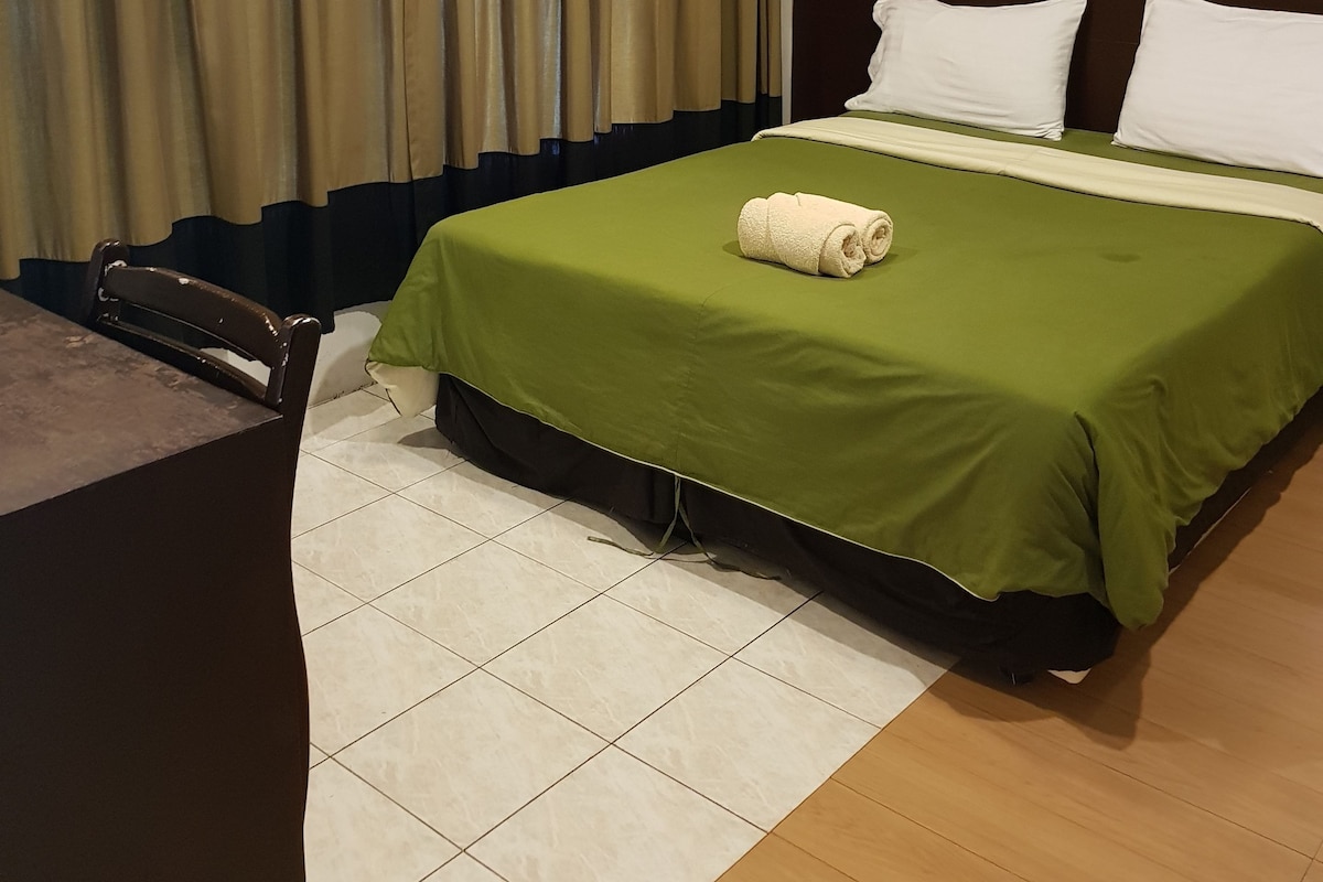A hotel room with a bed, a desk, and a chair.
