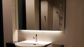 A modern bathroom with a white sink, a mirror above it, and a shower area. - B & B Patong Beach House (Patong)