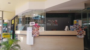 A reception desk with a glass partition, a "Welcome Open" sign, and various promotional posters. - B & B Patong Beach House (Patong)