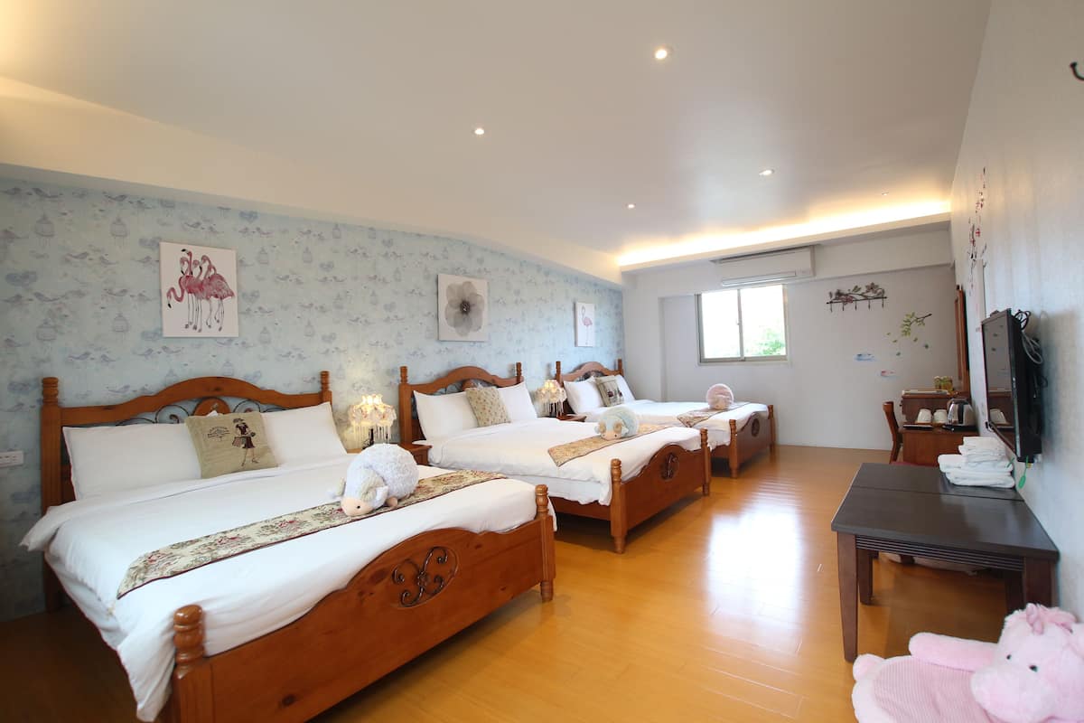 A hotel room with three wooden beds, a wooden table, and a television.