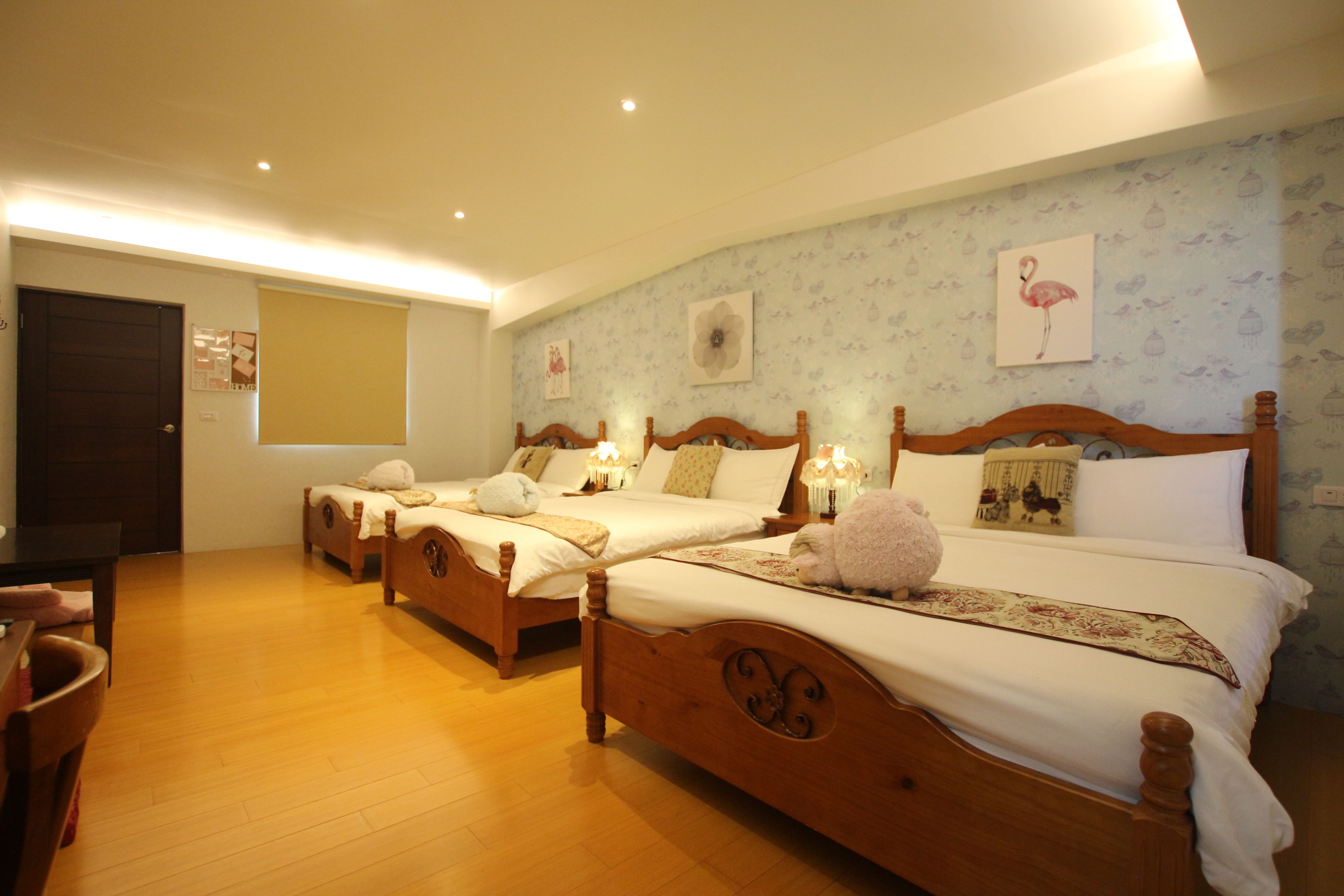 Une chambre d’hôtel avec trois lits en bois, un bureau en bois et une grande fenêtre.