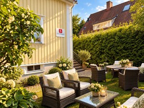 A patio area with wicker furniture, a glass table, and potted plants. - 5:ans Bed & Breakfast (Gothenburg)