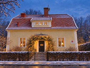 A two-story house with a red-tiled roof, a front door with a wreath, and a small Christmas tree. - 5:ans Bed & Breakfast (Gothenburg)