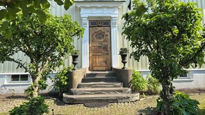 Un edificio con puerta de madera, escalones de piedra y plantas en macetas.